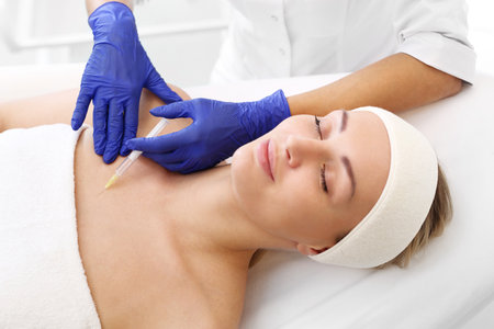 A patient in a cosmetic clinic, a beautician performs an injection procedure.の写真素材