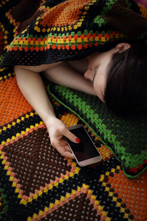 Loneliness and longing. A woman is sleeping while holding a phone in her hand.の写真素材