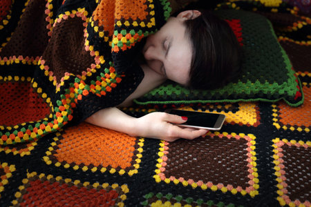 Attachment to new technologies. A woman is sleeping while holding a phone in her hand.の写真素材