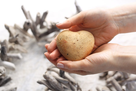 The woman is holding a stone heart in her handsの写真素材