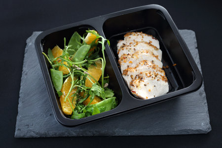 Dinner meal in a box diet. Chicken in herbs with green saladの写真素材