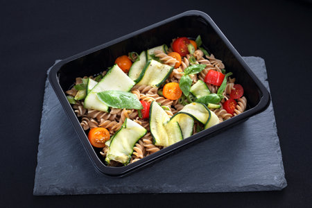 Delicious pasta salad with green lettuce, tomatoes and roasted chicken.の写真素材