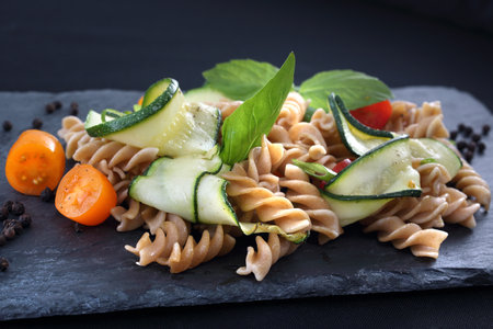 Delicious pasta salad with green lettuce, tomatoes and roasted chicken.の写真素材