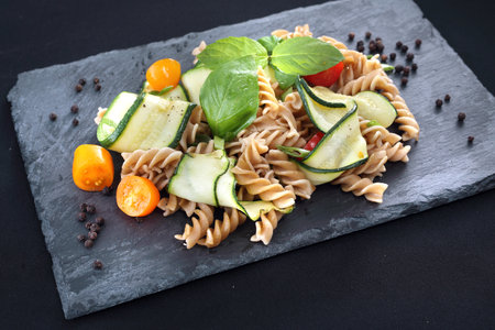 Delicious pasta salad with green lettuce, tomatoes and roasted chicken.の写真素材