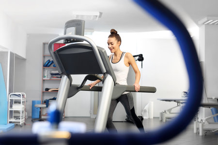 A young woman in an exercise room is running on an automatic treadmill.の写真素材