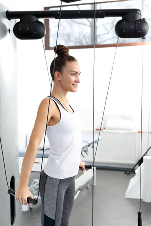 Rehabilitation and exercises of a young woman on a training machine with a load.の写真素材