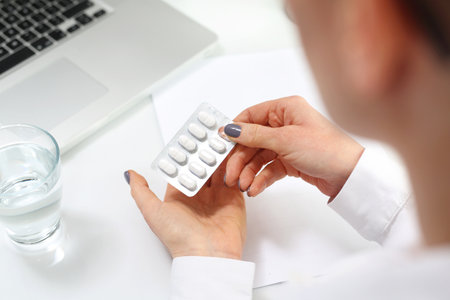 A woman at work is taking painkillers.の写真素材