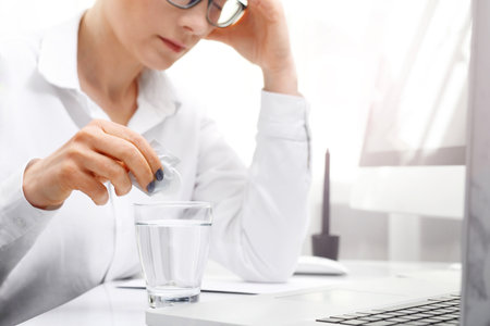 Painkiller tablet. A woman at work dissolves the effervescent painkiller tablet.の写真素材