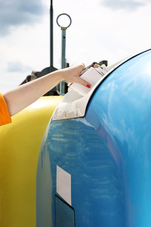 Recycling, a woman throws paper waste into a blue containerの写真素材