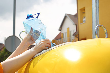 Recycling, a woman throws plastic waste into a yellow containerの写真素材