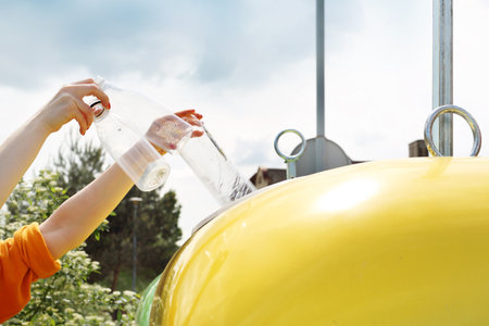 Recycling, a woman throws plastic waste into a yellow containerの写真素材