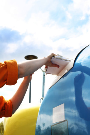 Recycling, a woman throws paper waste into a blue containerの写真素材