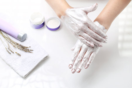 Hand spa. The woman puts a mask on the skin of the hand. Hand skin care.の写真素材