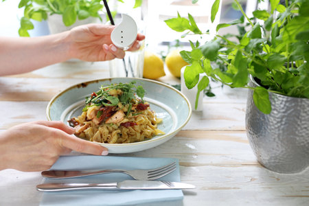 A woman in a restaurant eats pasta. Dish served in the restaurant tagliatelle spaghetti with salmon and dried tomatoes. Proposition of serving the dish.の写真素材