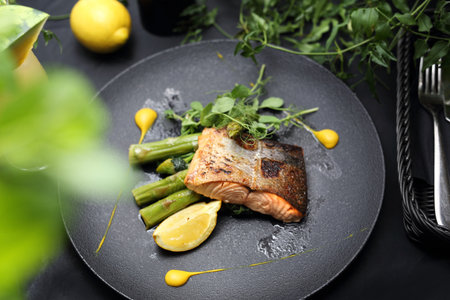 Baked salmon fillet with lemon sauce served on green asparagus. An elegant exquisite dish.の写真素材
