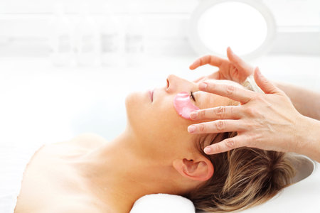 Relax in the beauty salon. Beautician performs facial massage, woman in a spa.の写真素材
