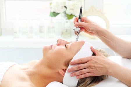Oxygen infufusion. The beautician performs an oxygen infusion treatment on a woman's skin. Care treatment, skin cleansingの写真素材
