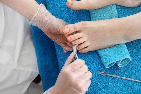 Woman's feet during pedicure, the beautician cuts cuticles and cuts nails with clippers.の写真素材