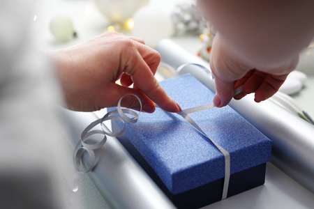 Woman wraps a present on white