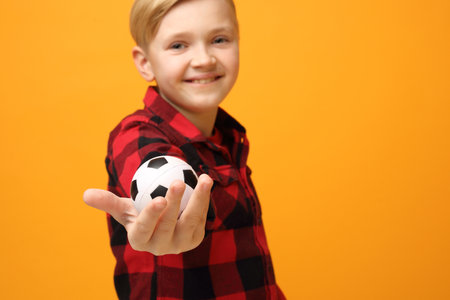 The boy is holding a small football ballの写真素材