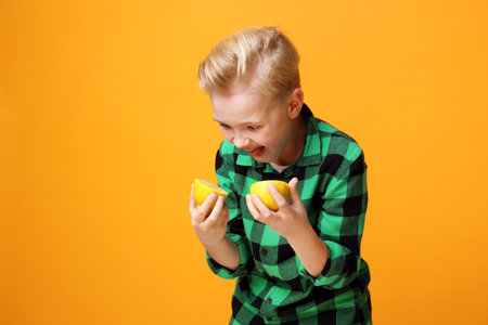 The boy eats a lemon, the child's funny faces.の写真素材
