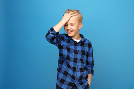 Great joy, a laughing child. Young handsome smiling caucasian boy in the red shirt on the blue...