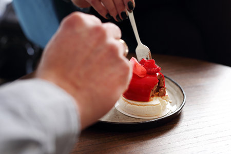 In love eat dessert. A woman and a man are eating sweet dessert hearts.の写真素材