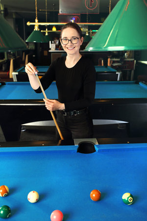 Billiard game. Woman plays billiards in a billiard club.の写真素材