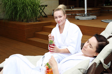Women relax in a luxurious spa. Two women are relaxing on sun loungers on a sunny summer dayの写真素材
