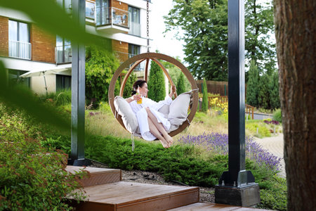 Woman relaxing at the spa. Young woman relaxes sitting on a hammock in the green garden.の写真素材