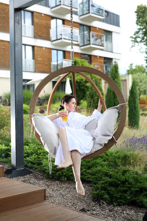 Relax in the garden. Young woman relaxes sitting on a hammock in the green garden.の写真素材