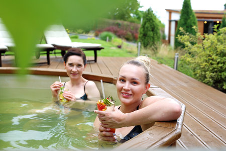 Bath in a garden tub. Two beautiful women enjoy a relaxing bath in the tub. Girl friends at the spa.の写真素材