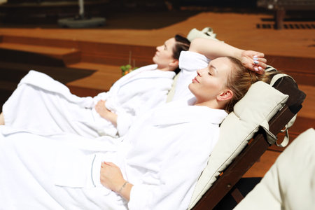 Women at the hotel pool. Two women are relaxing on sun loungers on a sunny summer dayの写真素材