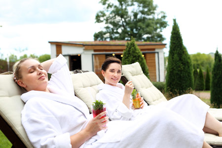Spa vacation. Two women are relaxing on sun loungers on a sunny summer dayの写真素材