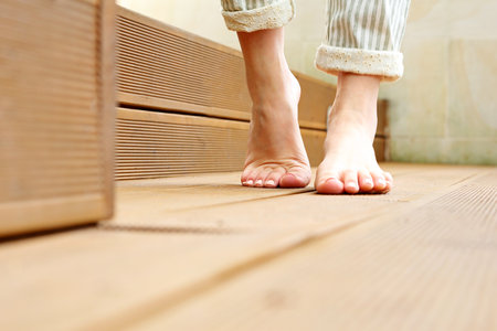 Feet. Beautiful bare female feet. A woman is standing barefoot on wooden floorboards.の写真素材