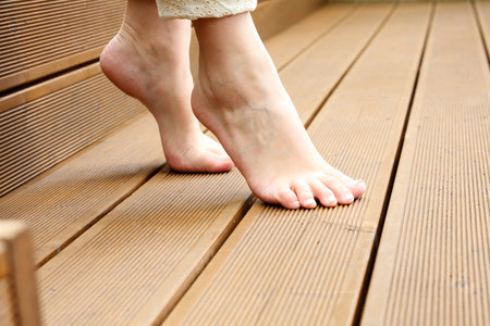 Feet. Beautiful bare female feet. A woman is standing barefoot on wooden floorboards.の写真素材