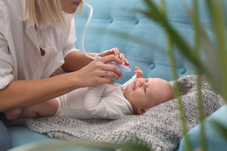Runny nose in an infant. Mom picks up a runny nose with an aspirator. Baby care.