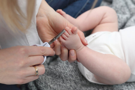 Cutting baby's nails. Baby care, mom cuts her nailsの写真素材