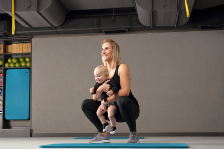 Training with a baby. A woman trains with a child in a fitness room.の写真素材