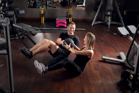 Training in the gym. The woman trains with a personal trainer.の写真素材
