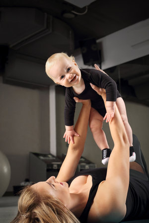Training with a baby. A woman trains with a child in a fitness room.の写真素材