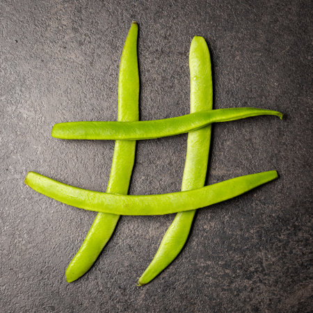 Flatlay of hashtag symbol made of long green beans lying on dark table