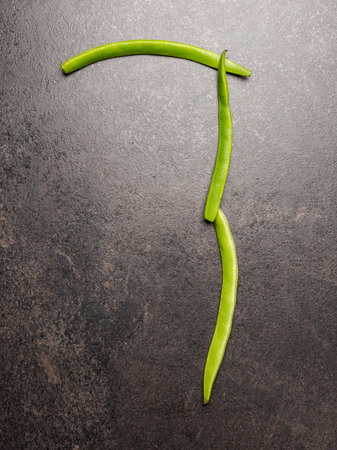 Flatlay of the digit seven laid out with long green beans on dark tableの写真素材
