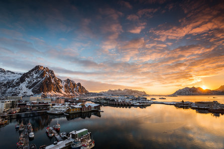 View over the port of Svolvaer on the Lofoten islands in colorful early morning sunrise in winter with snowの写真素材