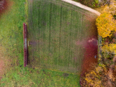 Top down aerial drone shot of empty grass field soccer playground area in autumn with colored tree foliage in public parkの写真素材