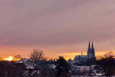 The cathedral St. Peter in Regensburg on cold winter morning in December with fresh snow on the roofs and spiersの写真素材