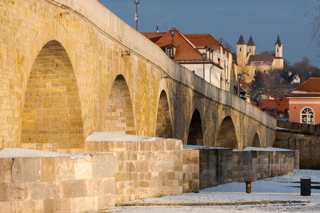 The famous Stone Bridge in the bavarian town Regensburg on sunny winter morning with snowの写真素材