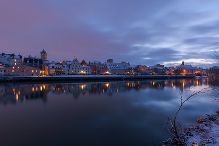 Cathedral, stone bridge and old town of Regensburg on the danube river in winter with fresh snowの写真素材