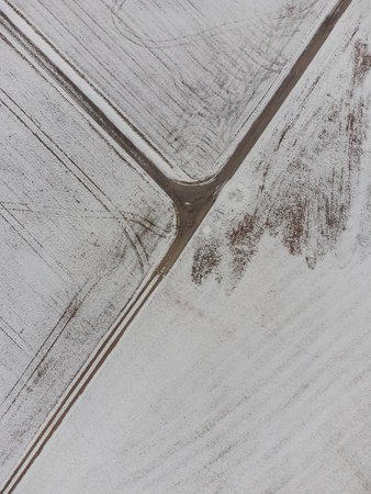 Aerial top down shot of three-way intersection between fields in rural area in winter with snow