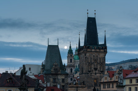 Bridge tower of Charles bridge in Prague over the Vlatva river at night with full moon in sky behind cloudsの写真素材